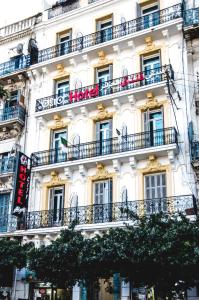 un edificio blanco con balcones y una señal en él en City Hotel Alger, en Argel