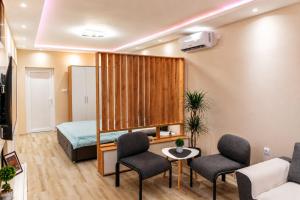 a living room with a bed and chairs in a room at Apartman Harmony in Prijedor