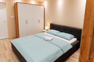 a bedroom with a bed with a blue blanket and a mirror at Apartman Harmony in Prijedor