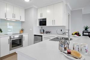 a kitchen with white cabinets and a white counter top at Beachfront Breeze - sea views for days in New Plymouth +17 photos
