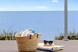 a basket with a towel and a book and glasses at Beachfront Breeze - sea views for days in New Plymouth