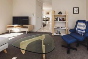 a living room with a glass table and a chair at Sail-Shaped Townhouse in New Plymouth in New Plymouth