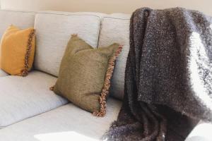 a white couch with pillows and a blanket on it at Sail-Shaped Townhouse in New Plymouth in New Plymouth