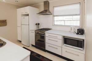a white kitchen with a stove and a refrigerator at Sail-Shaped Townhouse in New Plymouth in New Plymouth +20 photos