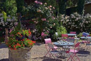a table and chairs in a garden with flowers at Hostellerie de la Motte jean in Saint-Coulomb