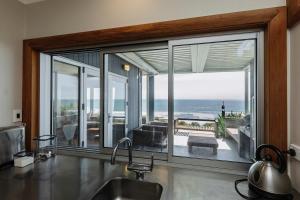 a kitchen with a large window with a view of the ocean at Clifftops - oceanfront retreat in Oakura Beach in Oakura
