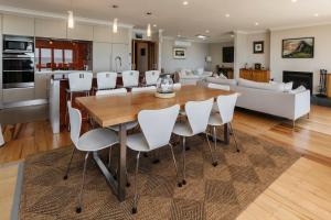 a kitchen and living room with a wooden table and chairs at Clifftops - oceanfront retreat in Oakura Beach in Oakura