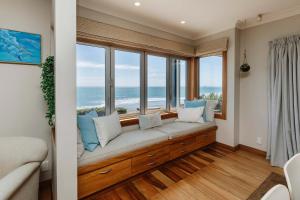 a room with a window seat with a view of the ocean at Clifftops - oceanfront retreat in Oakura Beach in Oakura