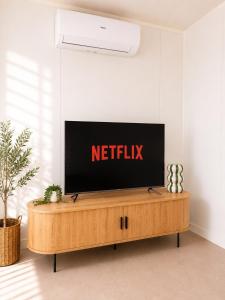 a flat screen tv sitting on top of a wooden entertainment center at Gem on Matrix - Hidden Retreat with Deck in Lightning Ridge