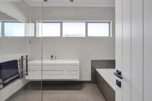 a bathroom with a sink and a glass shower at Executive On Parkview - 3BR modern family home in New Plymouth