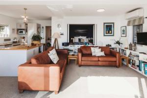a living room with two couches and a kitchen at Te Moana Waterfront - beachside accommodation in New Plymouth