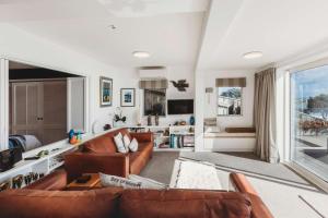 a living room with brown leather furniture and a large window at Te Moana Waterfront - beachside accommodation in New Plymouth