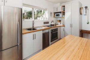 a kitchen with white cabinets and a stainless steel refrigerator at Te Moana Waterfront - beachside accommodation in New Plymouth +16 photos