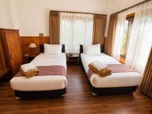 two beds in a room with wooden floors and windows at Tshang Tshang Villa in Paro