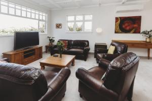 a living room with leather furniture and a flat screen tv at The Front Office - charming 3BR heritage home in New Plymouth
