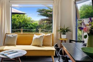 a living room with a yellow couch and a table at Butlers Studio Two in Oakura