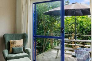 an open door to a patio with an umbrella at Butlers Studio Two in Oakura +10 photos