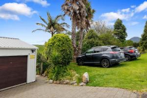 two cars parked in a yard next to a garage at Butlers Studio Two in Oakura