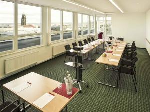a row of tables and chairs in a room with windows at ibis Dresden Zentrum in Dresden