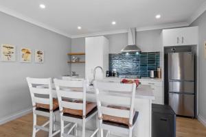 a kitchen with white chairs and a kitchen island at Weld Cottage - Sustainable lifestyle property in New Plymouth