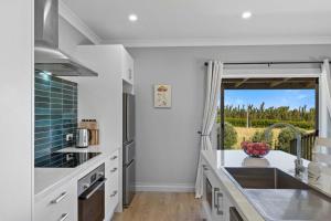 a kitchen with white counters and a large window at Weld Cottage - Sustainable lifestyle property in New Plymouth