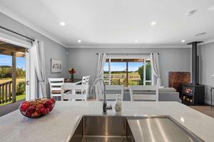 a kitchen with a sink and a living room at Weld Cottage - Sustainable lifestyle property in New Plymouth +14 photos