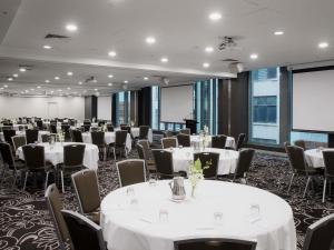 a conference room with tables and chairs and a screen at Novotel Melbourne On Collins in Melbourne +146 photos