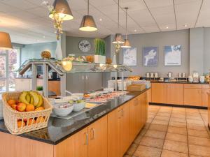 a large kitchen with fruits and vegetables on a counter at ibis Hotel Frankfurt Messe West in Frankfurt +66 photos