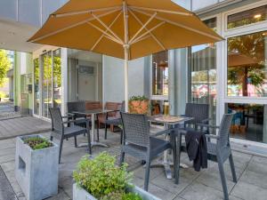 a patio with tables and chairs and an umbrella at ibis Hotel Frankfurt Messe West in Frankfurt