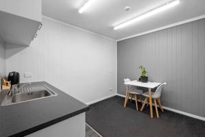 a kitchen with a sink and a table with chairs at Naki Nook - Accommodation Stratford in Stratford
