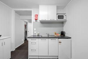a white kitchen with a sink and a microwave at Naki Nook - Accommodation Stratford in Stratford