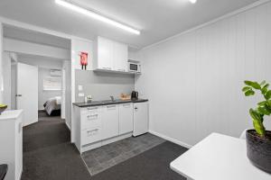 a kitchen with white cabinets and a sink in a room at Naki Nook - Accommodation Stratford in Stratford +10 photos