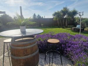 a table and two stools in a garden with purple flowers at ibis Pau Lescar in Lescar