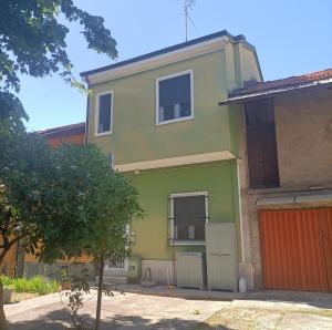 a green house with a red garage at La Stanza nella corte in Bollate