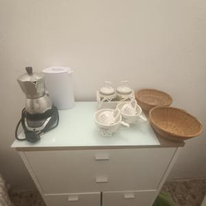 a white cabinet with cups and bowls on it at La Stanza nella corte in Bollate