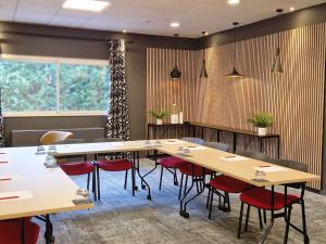 a conference room with wooden tables and red chairs at ibis Pau Lescar in Lescar