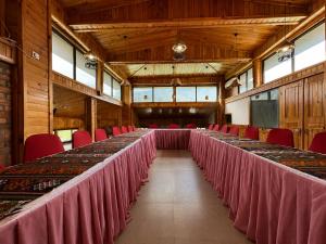 a long row of tables in a large room with red chairs at Tshang Tshang Villa in Paro