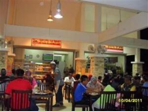 a group of people sitting at tables in a restaurant at Sea Front Hotel Port Dickson in Port Dickson