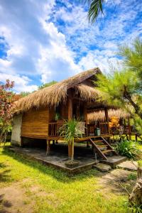 a hut with a thatched roof and palm trees at Garden Cottage in Gili Gede