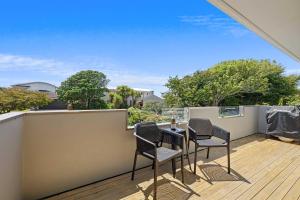 a patio with chairs and a table on a balcony at Seven By The Sea - stylish apartment near port in New Plymouth