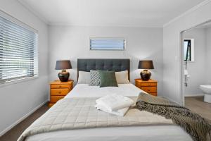 a bedroom with a large bed and two lamps and a sink at Seven By The Sea - stylish apartment near port in New Plymouth