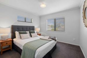 a bedroom with a large bed and two windows at Seven By The Sea - stylish apartment near port in New Plymouth +8 photos