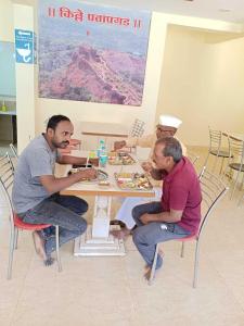 a group of men sitting around a table eating food at Hotel Sunrise, Panchgani in Panchgani