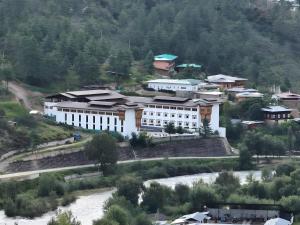 a large white building on a hill next to a river at Resort Thim -Dorji Paro RiverFront in Paro