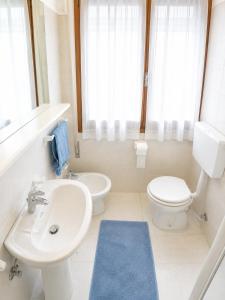 a white bathroom with a sink and a toilet at Condominio Sole - Agenzia Cocal in Caorle