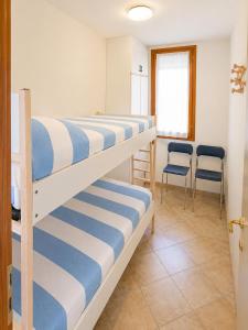 two bunk beds in a room with two chairs at Condominio Sole - Agenzia Cocal in Caorle