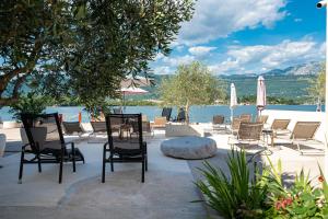 a group of chairs and tables and umbrellas and water at Dubravcevic Residence in Tivat