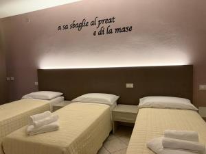 a room with three beds and a sign on the wall at Rosario House in Comacchio