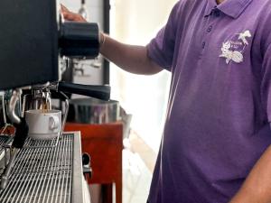 a man in a purple shirt is making a coffee cup at BougainVilla - Oceanfront villa with Cook, ideal for Weddings and Events in Keramas +100 photos
