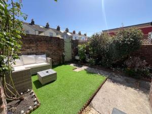 a small garden with a couch and grass at Number 29 in Melcombe Regis
